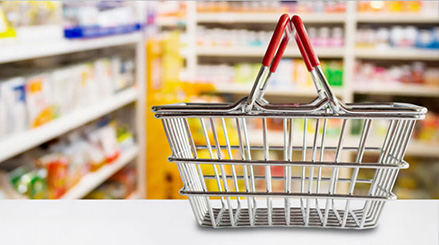 Small shopping basket on a countertop with shelves full of OTC items in the background