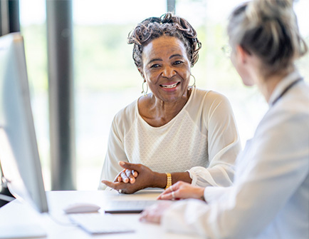 Senior african american woman with a doctor, sitting near a computer, smiling