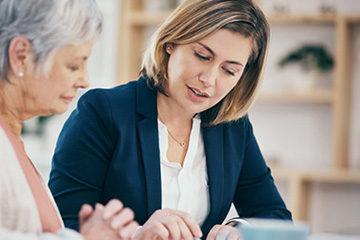 Senior woman and sales agent sitting at a table going over plan paperwork